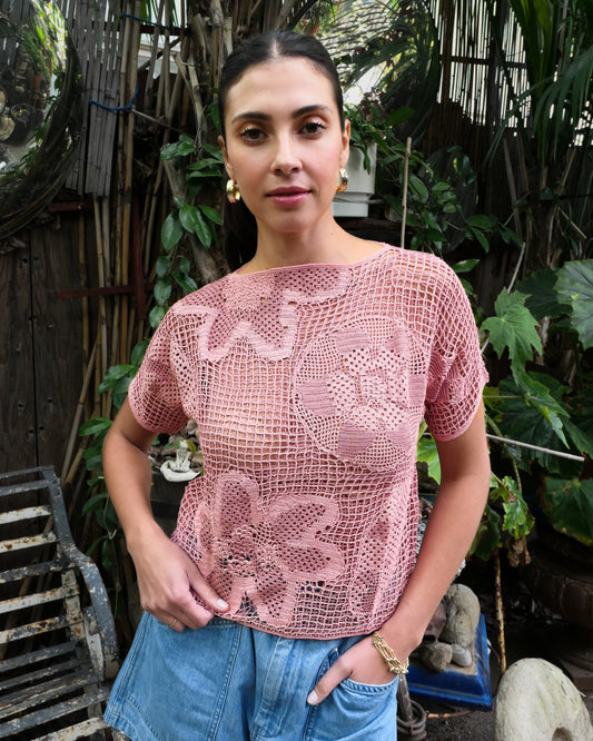 A Lim's Vintage original hand crocheted short sleeve top from the 1980s, with large abstract floral designs against a crisscross fishnet backdrop. A lightweight, breathable, and stretchable crochet top that can be dressed up or down and lends a charming, vintage accent to your everyday wardrobe. Color: Muted rose