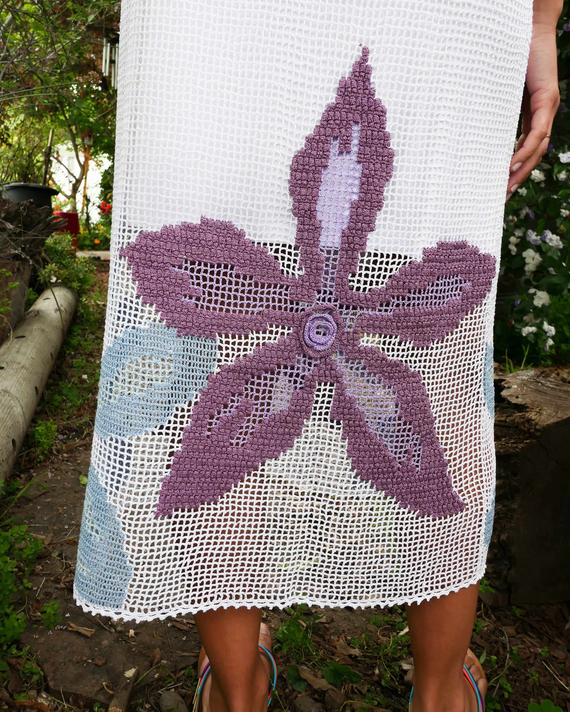 Closeup of bottom of white dress with purple flower design.  