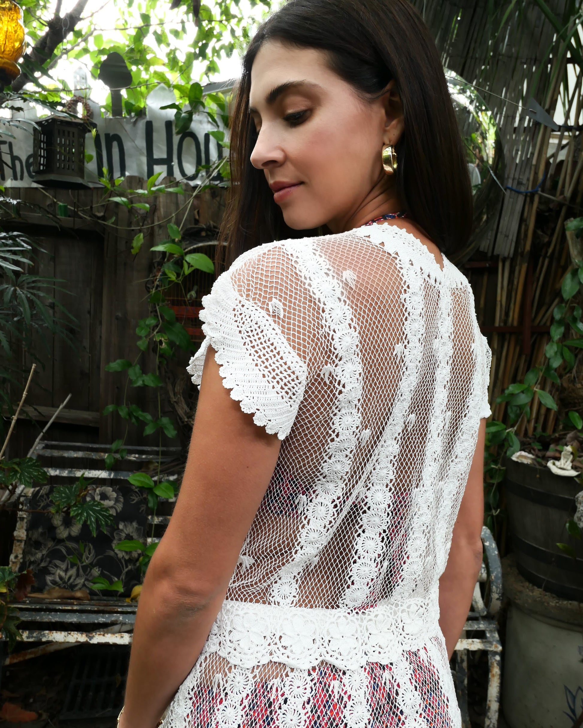 Back side view of top. Elegance and vintage charm meet in this sheer, lightweight Lim's Vintage 1980's original crochet button-up top made with fine cotton threads. Vertical stripes composed of connected pinwheel-like circles run up and down the body of the top, while delicate floral motif trim runs along the bottom hem. The collar and cap sleeves are adorned with simple hand crocheted trim.  Color: White