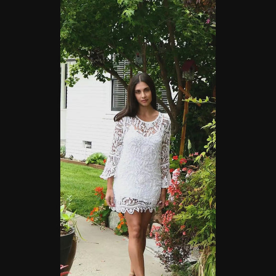 Video of model wearing white crochet mini dress with bell sleeves, made with Lim's Vintage floral and leaf motif crochet fabric. 