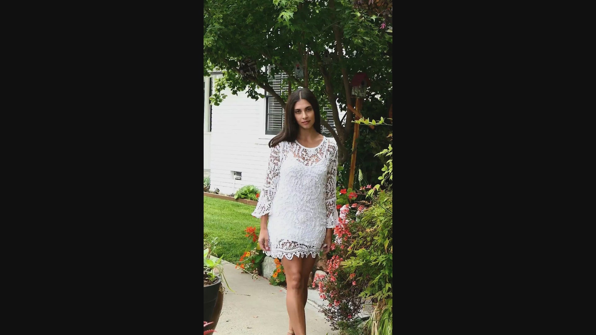 Video of model wearing white crochet mini dress with bell sleeves, made with Lim's Vintage floral and leaf motif crochet fabric. 