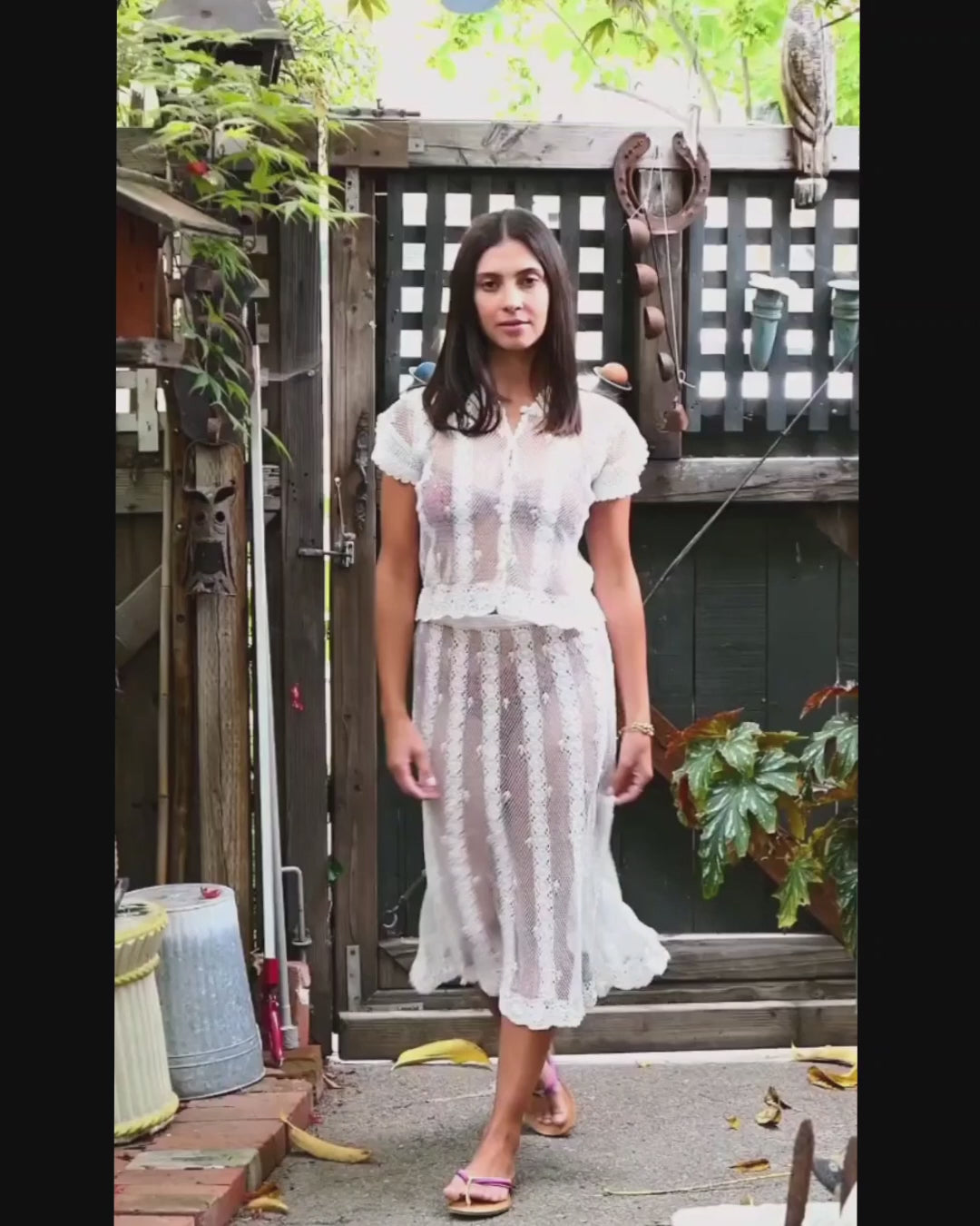 Video of model walking and twirling around in our two-piece hand crocheted button-up top and skirt set using sheer threads.  Color: White