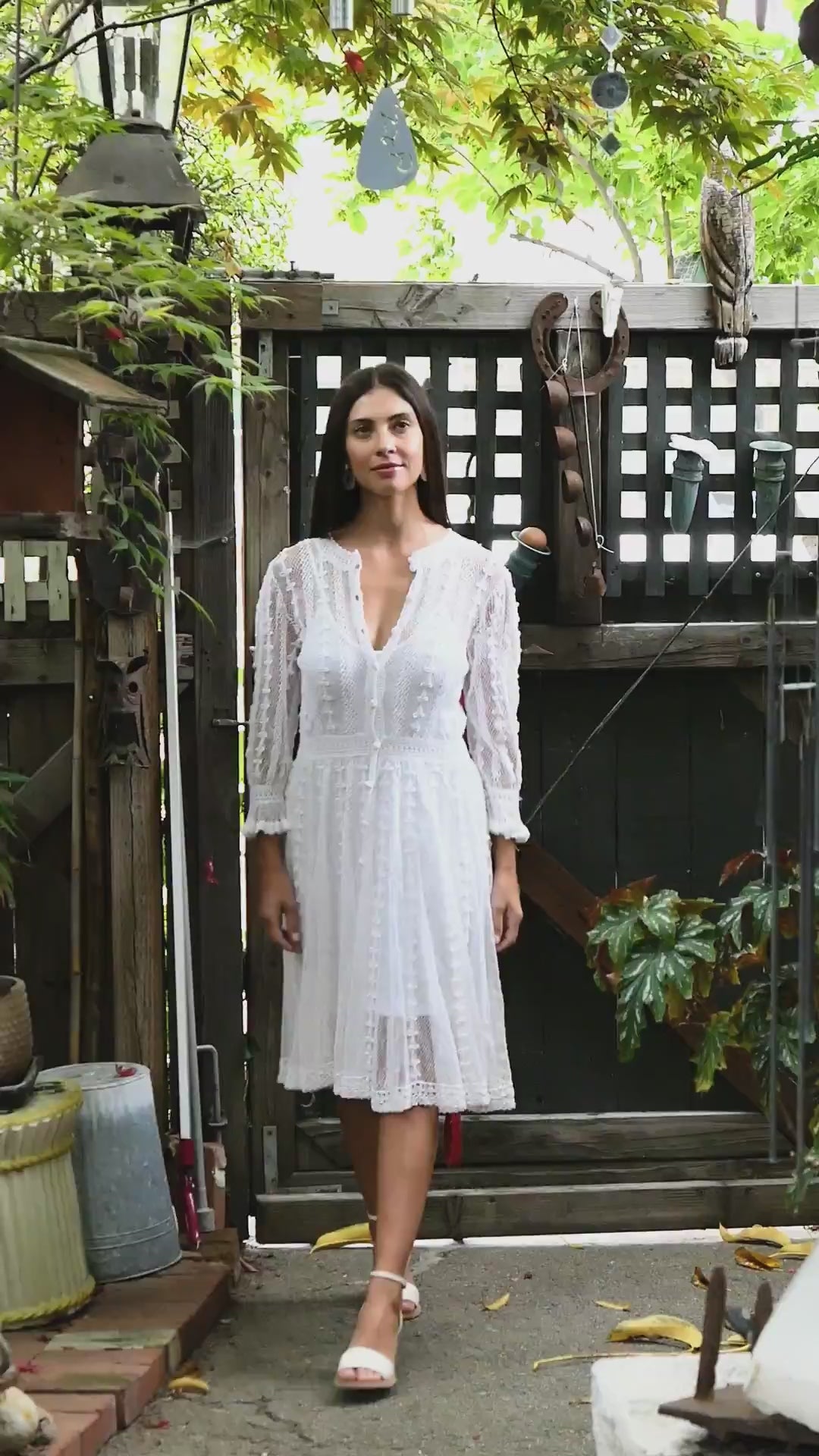 Video of model wearing Lim's Vintage cottage core crochet midi length dress.  Sheer hand crocheted dress with beautiful detail.  Long sleeves with ruffle border at the wrist. Buttons up the front or back and is reversible.