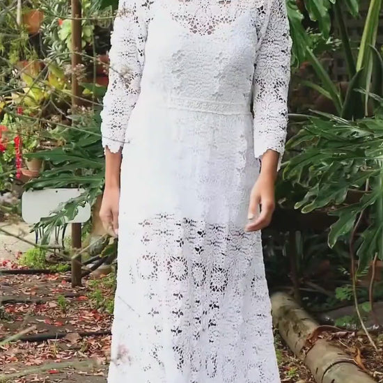 Video. A maxi dress with a classic silhouette, long sleeves, and a comfortable elastic waistband. Stitched together by hand using individual vintage doily lace pieces. Throw it over a white slip and a pair of open-toe heels for a stroll out on the town at your favorite beach destination. Color: White