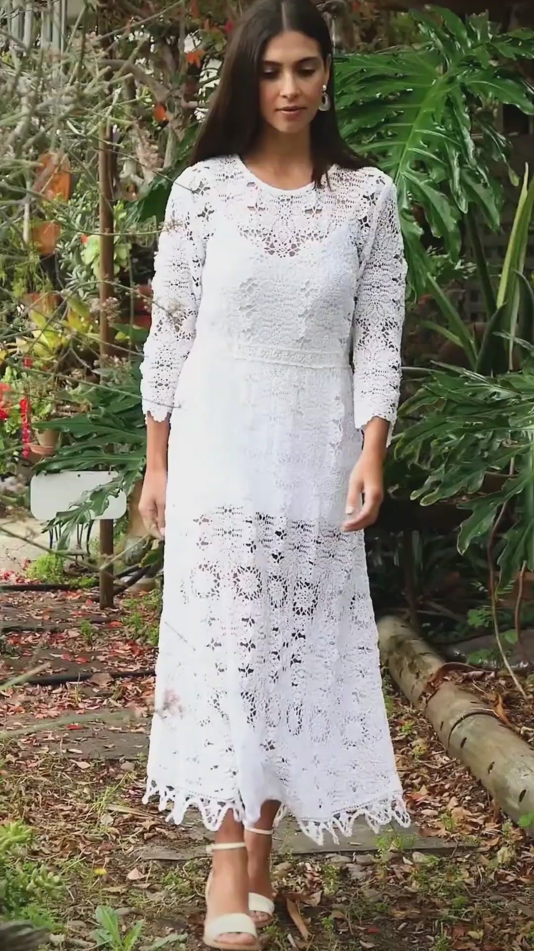 Video. A maxi dress with a classic silhouette, long sleeves, and a comfortable elastic waistband. Stitched together by hand using individual vintage doily lace pieces. Throw it over a white slip and a pair of open-toe heels for a stroll out on the town at your favorite beach destination. Color: White