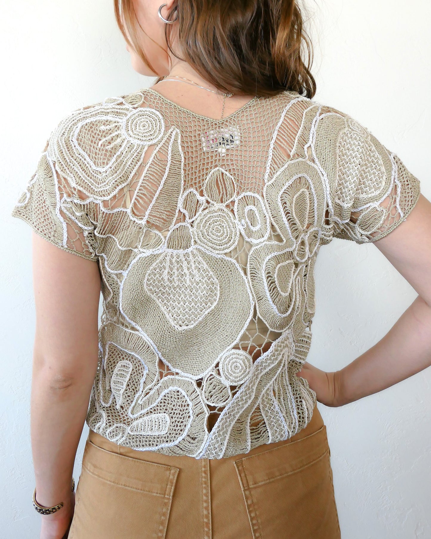 Back view of crochet top.  Refresh your wardrobe with this abstract floral patterned hand crocheted Lim's Vintage original high V-neck pullover top from the 1980s in neutral tones of taupe and white.  Pair it with jeans or shorts and sandals, or dress it up with a flowy skirt and wedges for a night out on a warm, summer's eve.