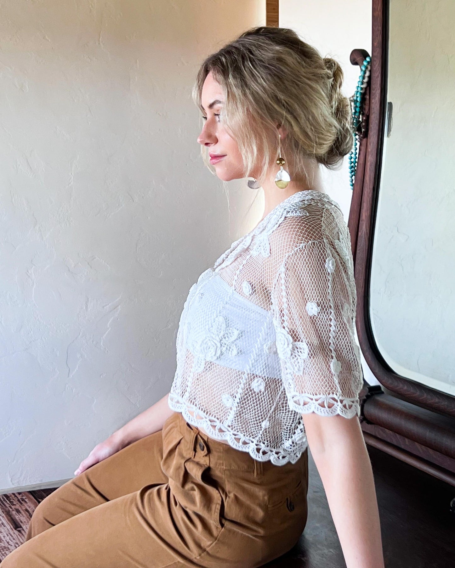 Side view of white crochet cardigan half sleeve top with carnation flowers crocheted throughout.  