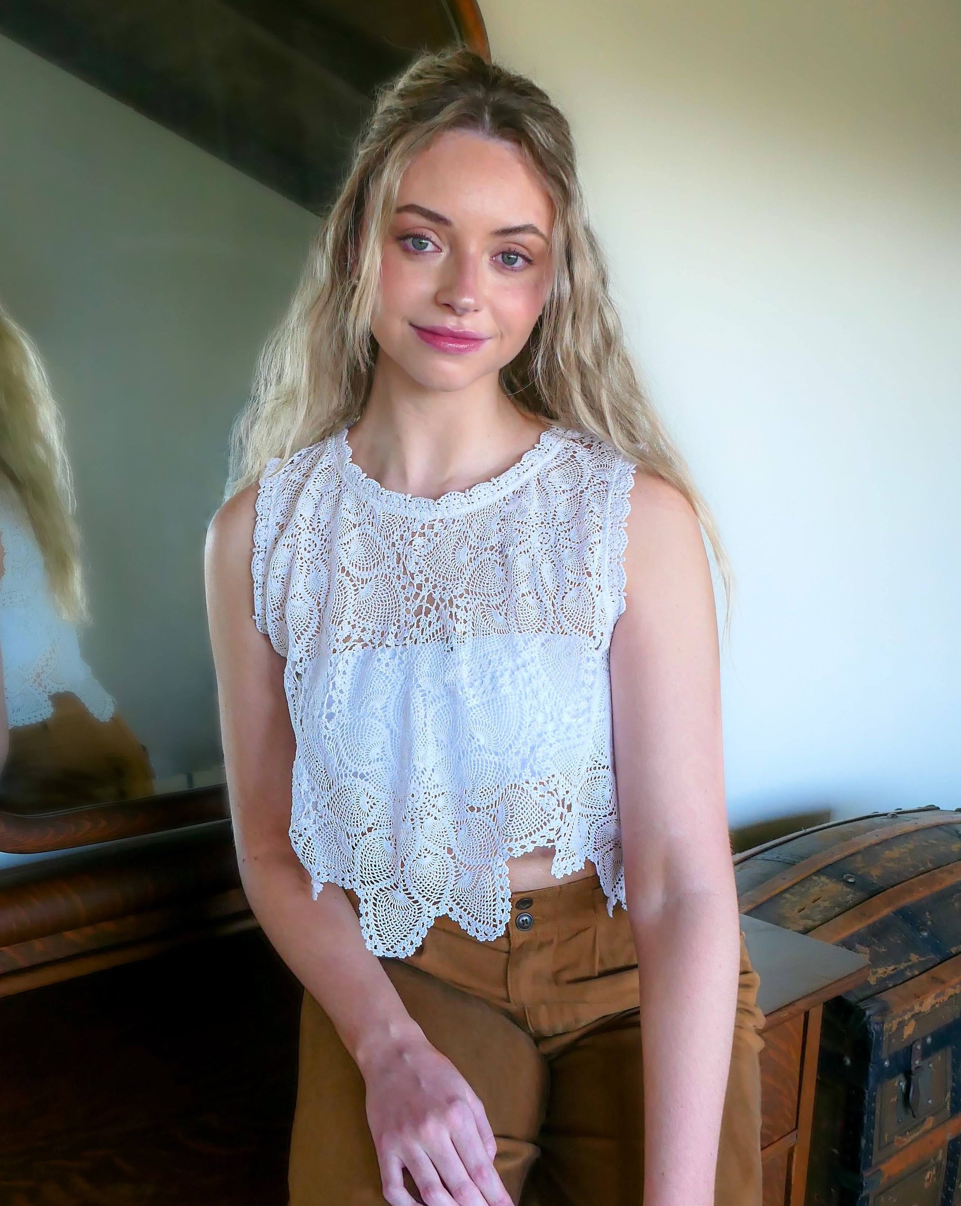 An ultra casual, hip, and boho-chic crop tank top made with interconnected flower doilies reminiscent of the white lotus, which symbolizes peace, tranquility, and calmness.  Lace trim at the collar and sleeve. 