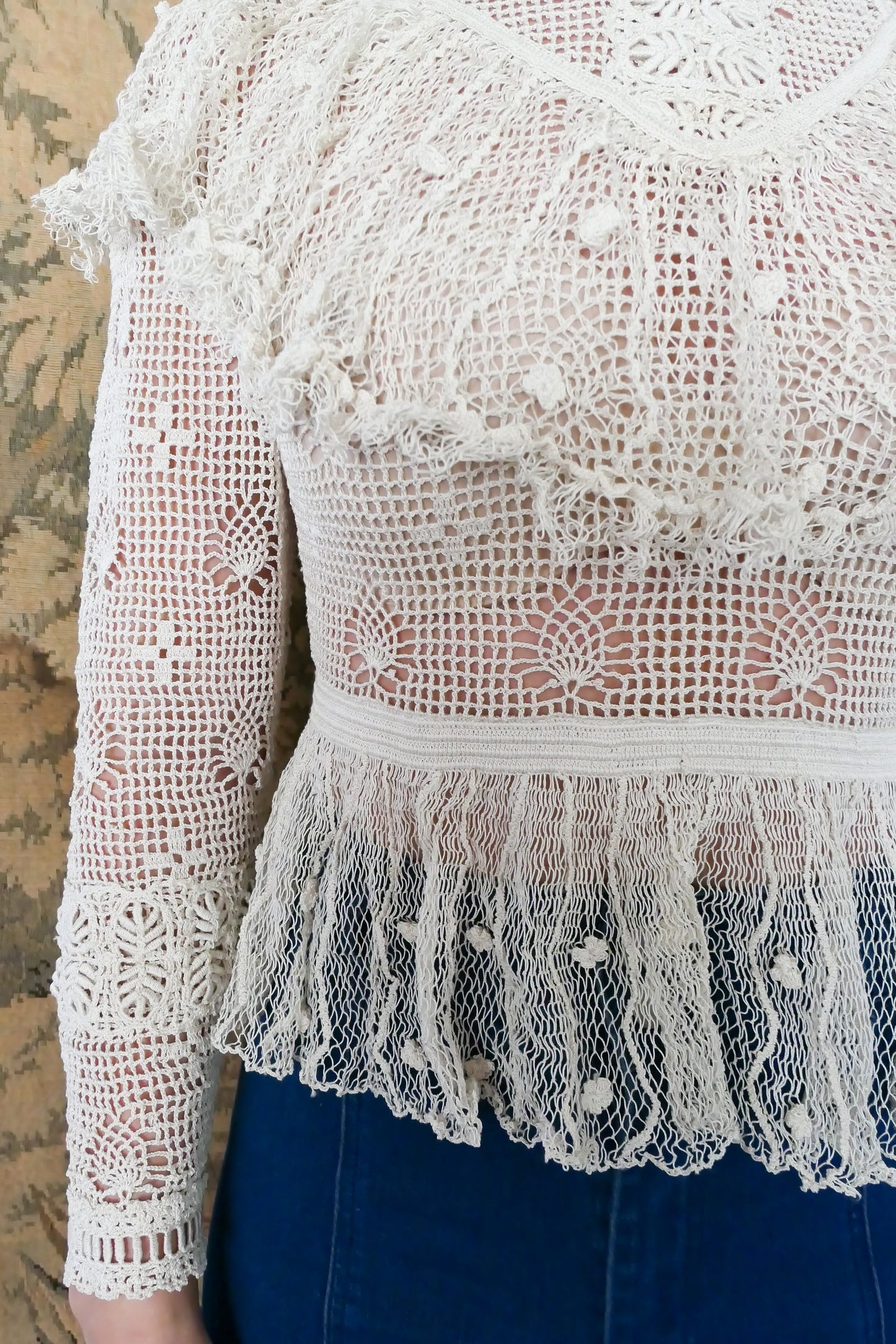 Closeup view of ruffled flared bottom hem of top made with sheer fishnet-like crochet material..  Waist is fitted.  