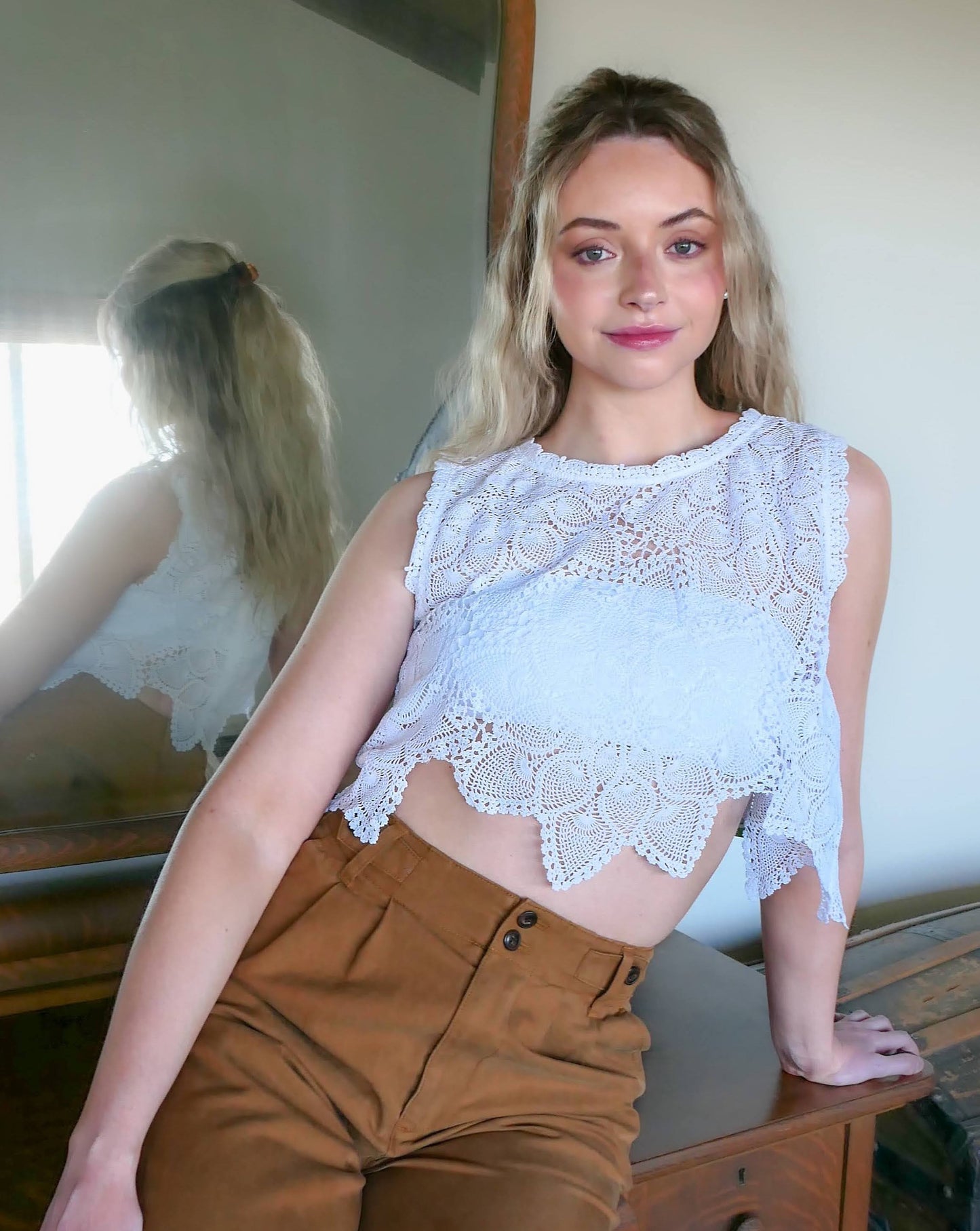 An ultra casual, hip, and boho-chic crop tank top made with interconnected flower doilies reminiscent of the white lotus, which symbolizes peace, tranquility, and calmness.  Lace trim at the collar and sleeve. 