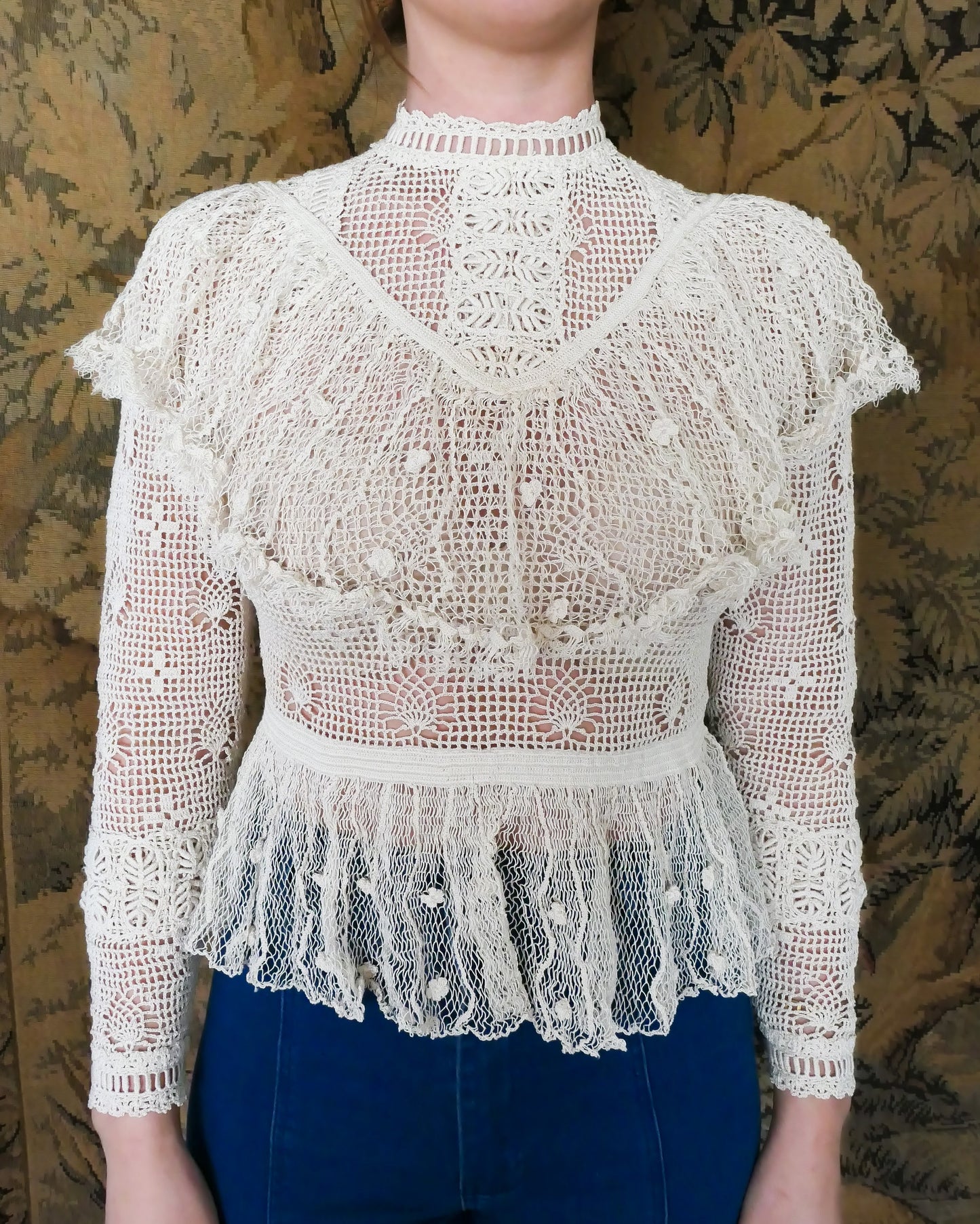 A Lim's original crochet top from the 1980s. Slightly thicker threads were used to crochet the body of the top, and very fine threads give the ruffled parts a lightweight, feminine touch. High Victorian neckline, a beautiful, intricate trim on the sleeves and chest, and a fitted waist and flared hem to create a flattering silhouette.  The top is reversible and can be worn with the buttons going down the front or back. This is truly one-of-a-kind, vintage, and our last available piece left!  Natural color. 