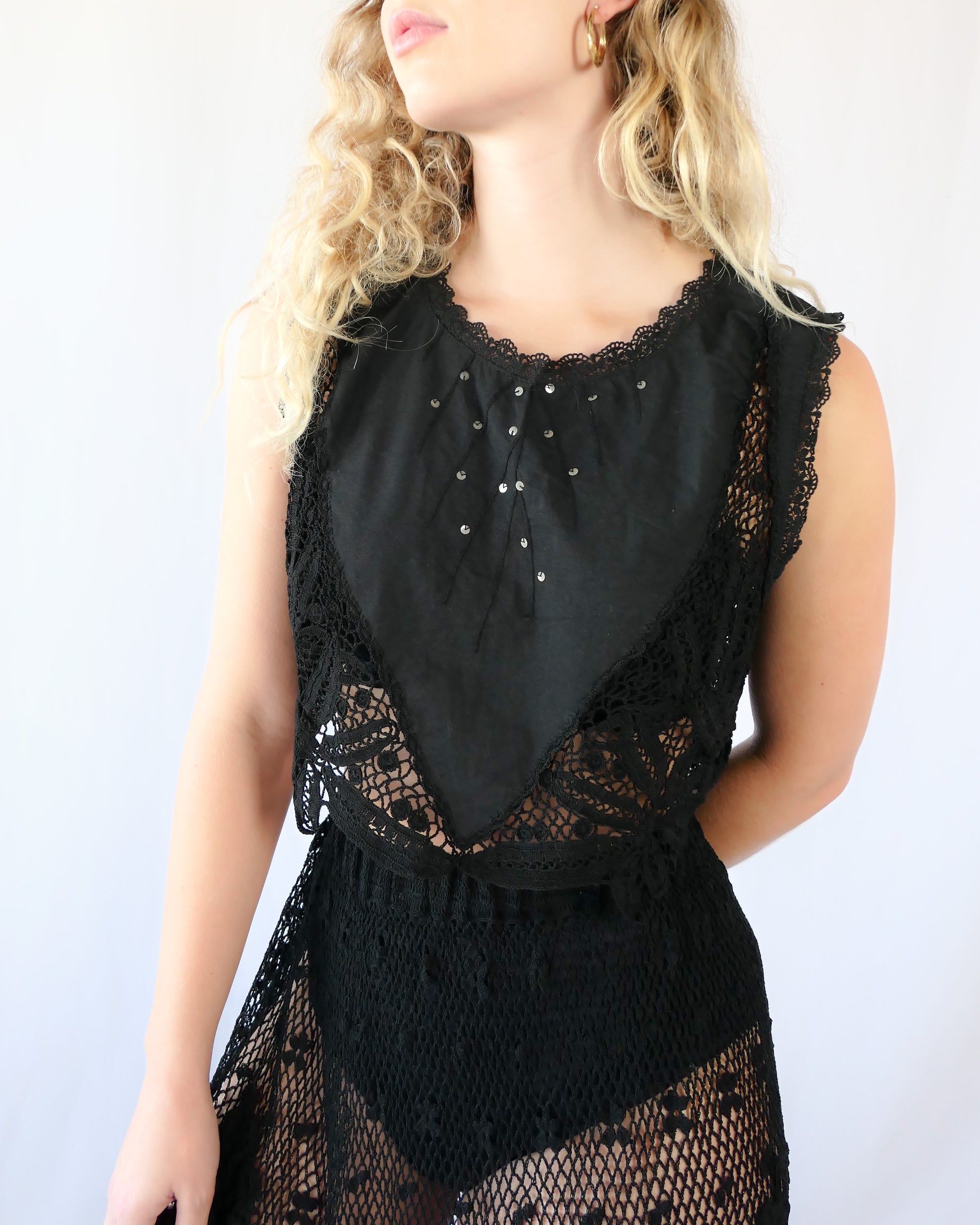 Rock on with this seductive black tank crop top made of vintage fabric with embroidered detail, sequins, and beautiful hand crochet work. Wear it together with one of our Lim's Vintage black crochet maxi length skirts for a festive goth vibe, or pair it with a black skirt or jeans and boots or sandals for a more casual look.  Measurements:  Bust 37” Waist 36" Length 15” Size: Small to Medium  Color: Black  Material: 100% cotton