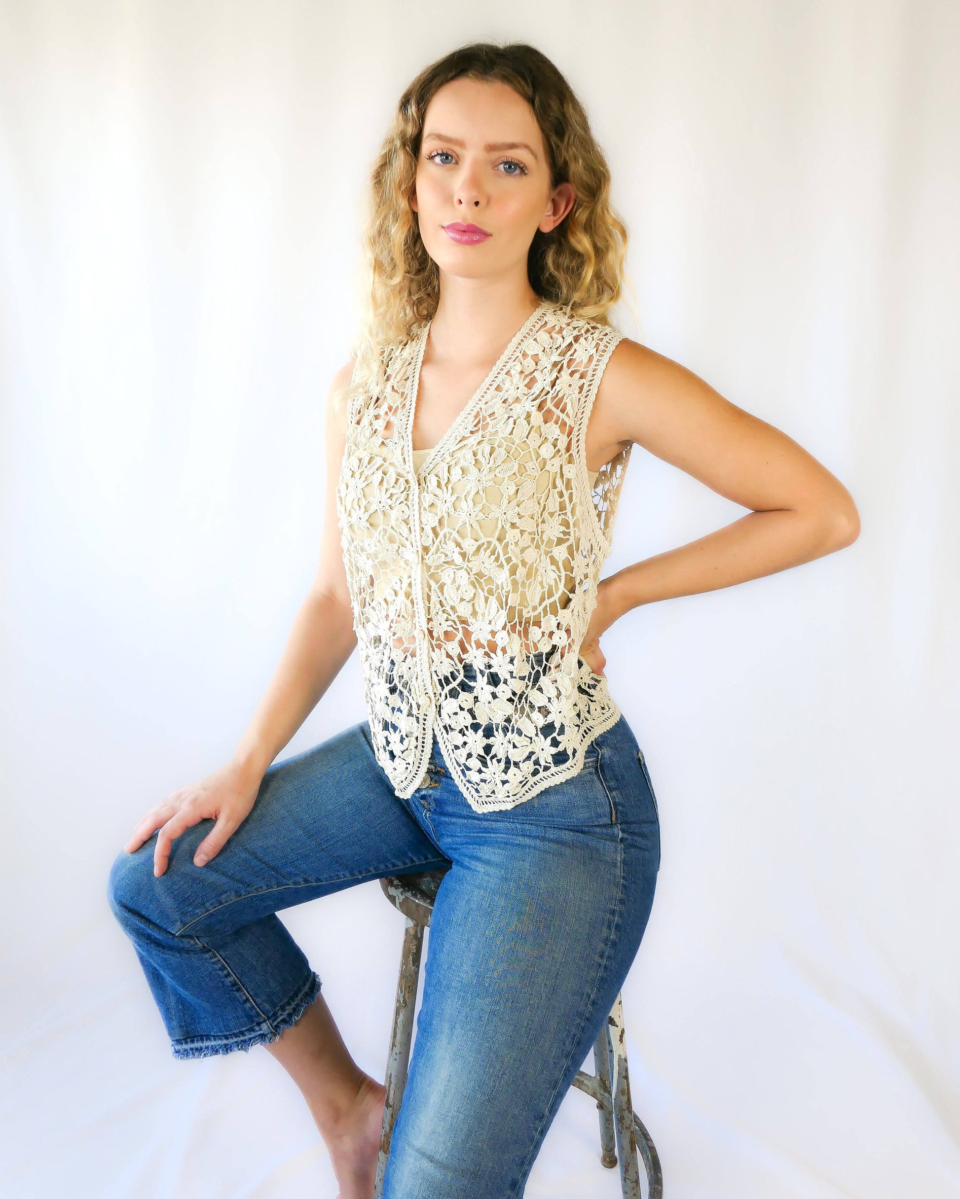 A Lim's Vintage original hand crocheted vest from the 1990s with a repeating jasmine floral and leaf motif throughout. Refined, delicate, and a vintage accent to your everyday wardrobe. Buttons up the front but can also be left open and worn over a bikini bra, tank top, or even a long sleeve shirt or blouse during cooler months. Due to the handmade nature of this vest, the length and bust circumference may vary slightly from piece to piece. Model is wearing natural color vest.