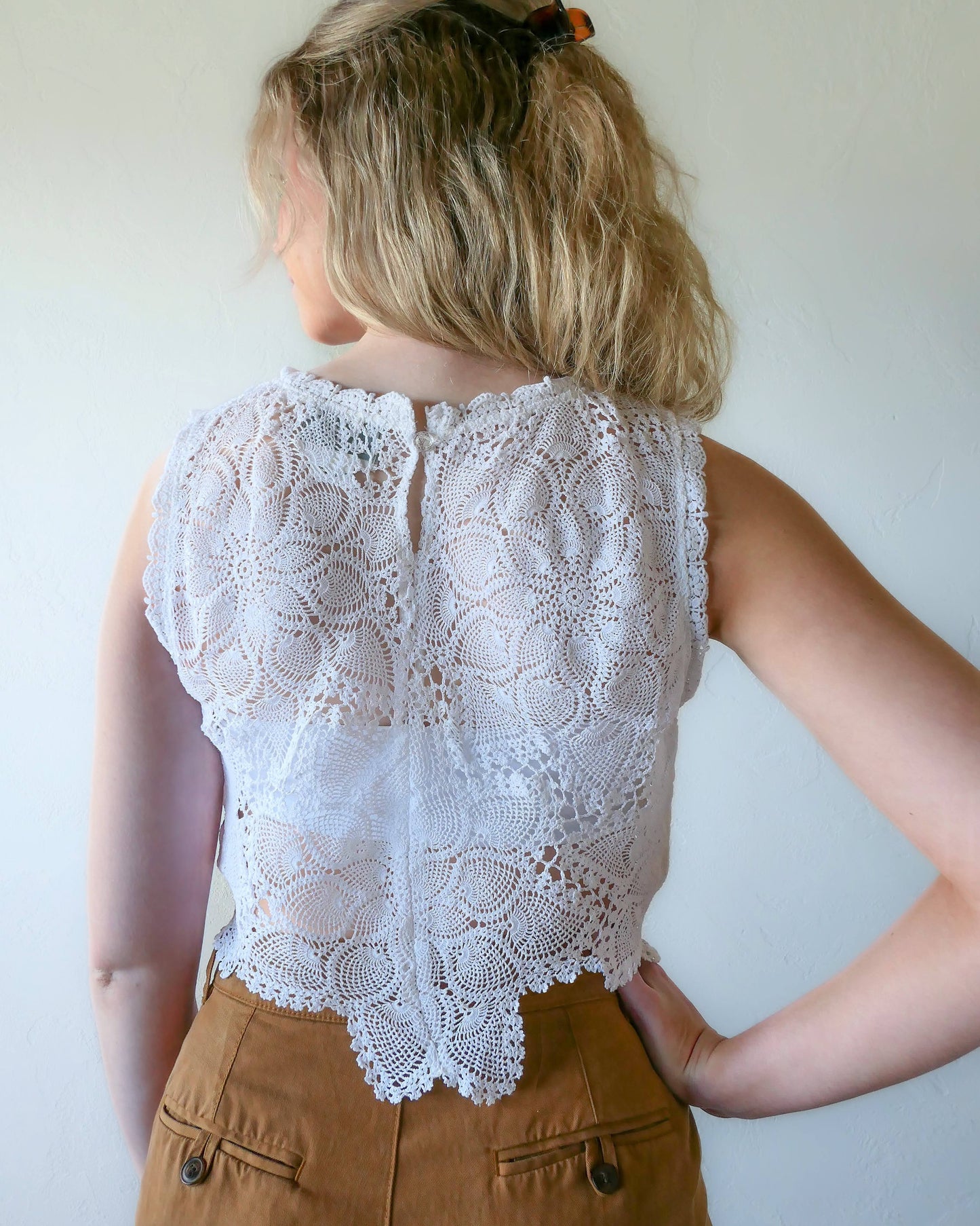 Back view of peace lotus motif crop tank top. An ultra casual, hip, and boho-chic crop tank top made with interconnected flower doilies reminiscent of the white lotus, which symbolizes peace, tranquility, and calmness.  Lace trim at the collar and sleeve. 