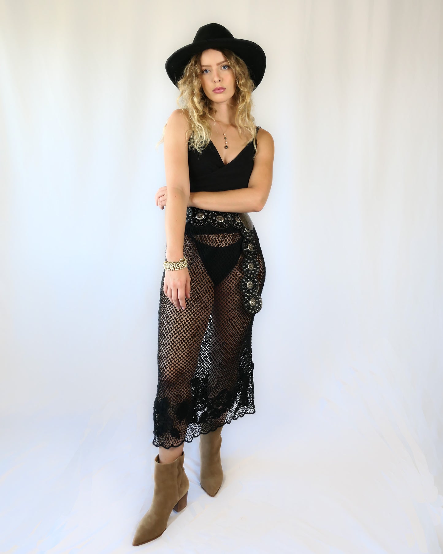 A Lim's Vintage 1980s original fishnet patterned skirt with intricate floral design and scalloped edging at the hem.  Provocative with a bohemian vibe, this hand crocheted skirt goes well with everything and comes with a comfortable elastic waistband.  Go rogue with boots and a cowboy hat, or wear it with heels and a silk camisole for a softer touch.    Size: Fits Small to Medium  Measurements:  Waist 26"- 30" (elastic) Hip 40” Length 31” Color: Black  Material: 100% ramie