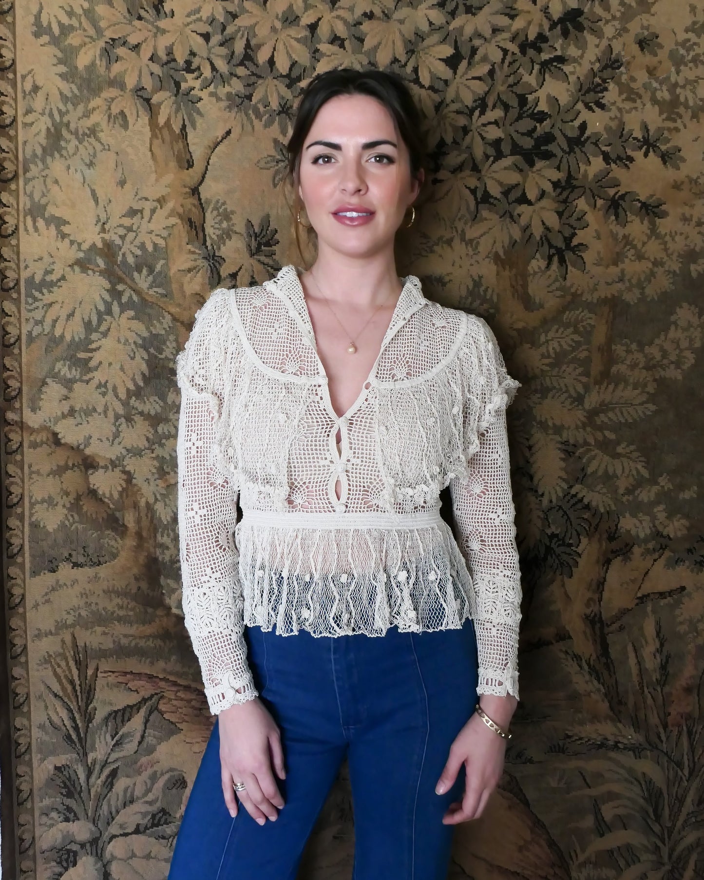 Photo of model wearing the top with buttons going up the front.  Lim's original crochet top from the 1980s. Slightly thicker threads were used to crochet the body of the top, and very fine threads give the ruffled parts a lightweight, feminine touch. High Victorian neckline, a beautiful, intricate trim on the sleeves and chest, and a fitted waist and flared hem to create a flattering silhouette.  The top is reversible and can be worn with the buttons going down the front or back. T