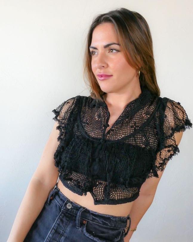 A super cool, super sassy hand crocheted fitted crop top in black with plenty of ruffles and frills for a fun, vintage inspired wardrobe.  Buttons up the front and crochet ruffles along the front covering the chest and over the shoulders.  The top buttons up and has a Victorian style collar.