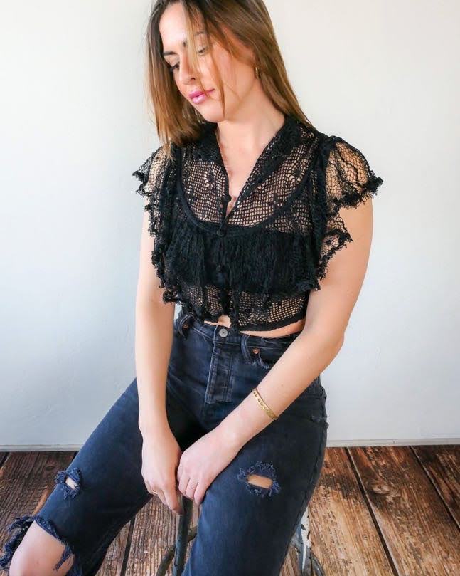 A super cool, super sassy hand crocheted fitted crop top in black with plenty of ruffles and frills for a fun, vintage inspired wardrobe.  Buttons up the front and crochet ruffles along the front covering the chest and over the shoulders. 