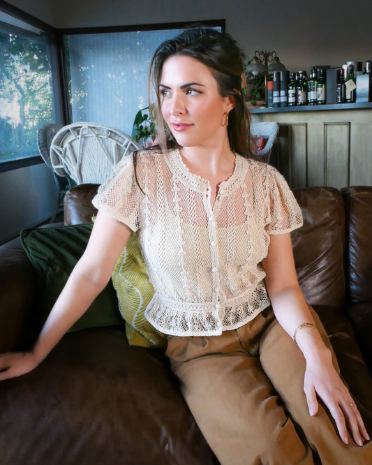 A Lim's original vintage crochet piece from the 1980s, this top was hand crocheted with very fine threads to create a delicate, lightweight, and transparent feel. Puffed sleeves, a high waist, and flared hem lend the top a whimsical yet tailored look. The top is reversible and can be buttoned up the front or back. Natural color.