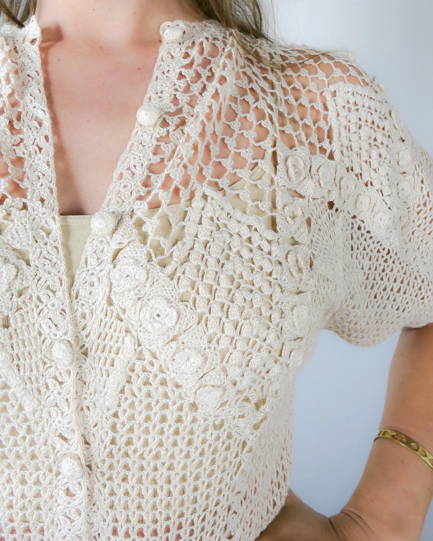 Closeup of collar. A classic Lim's Vintage hand crocheted button down top with a beautiful zig zag pattern on both the front and back, with lighter stitching around the chest and shoulders to bring a sense of lightness and space to the neckline. Petite flower buds sprout up from and accent the edges of the zig zag. This natural color top is versatile, comfortable, and adds a beautiful vintage accent to your wardrobe.