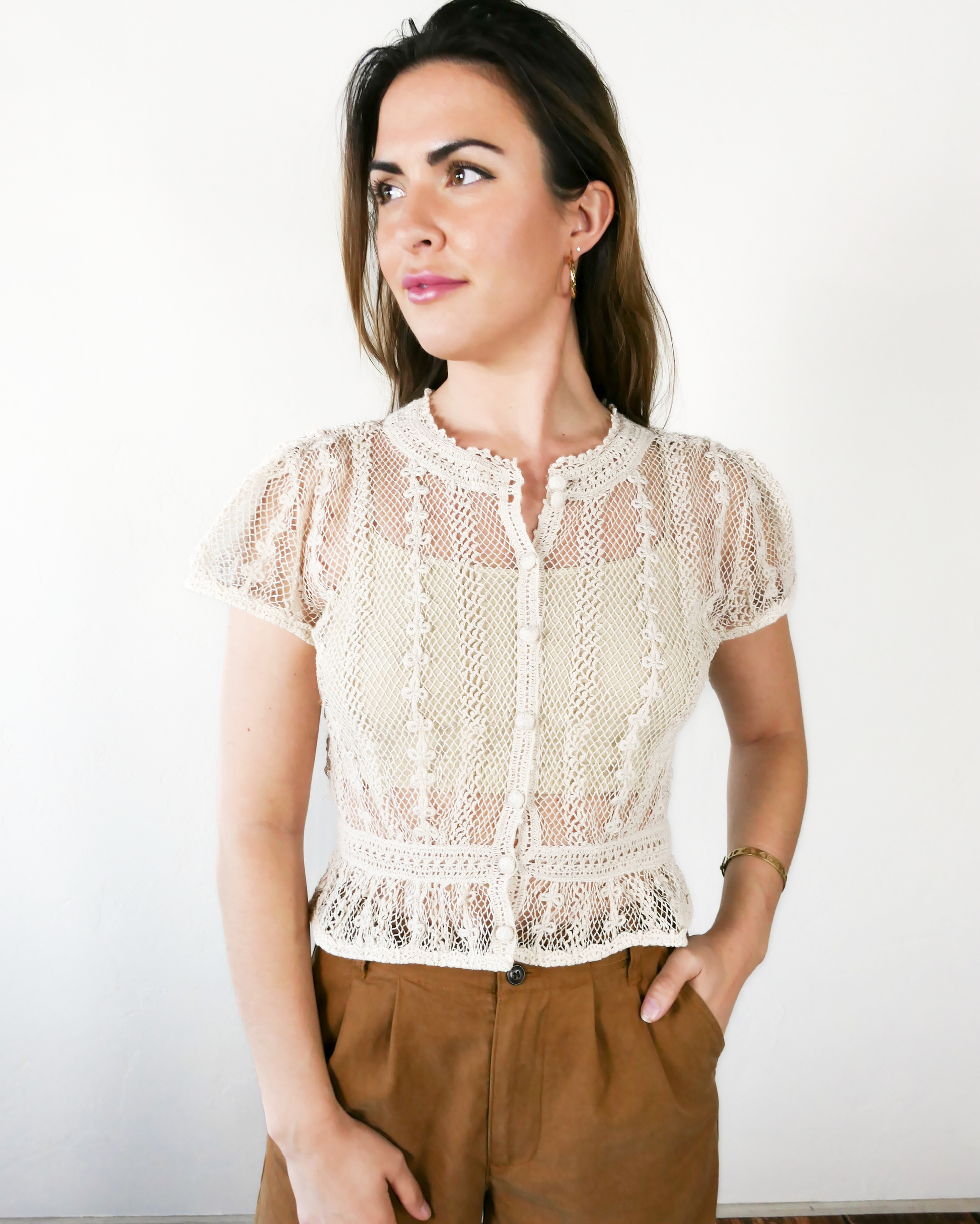 A Lim's original vintage crochet piece from the 1980s, this top was hand crocheted with very fine threads to create a delicate, lightweight, and transparent feel. Puffed sleeves, a high waist, and flared hem lend the top a whimsical yet tailored look. The top is reversible and can be buttoned up the front or back. Natural color.
