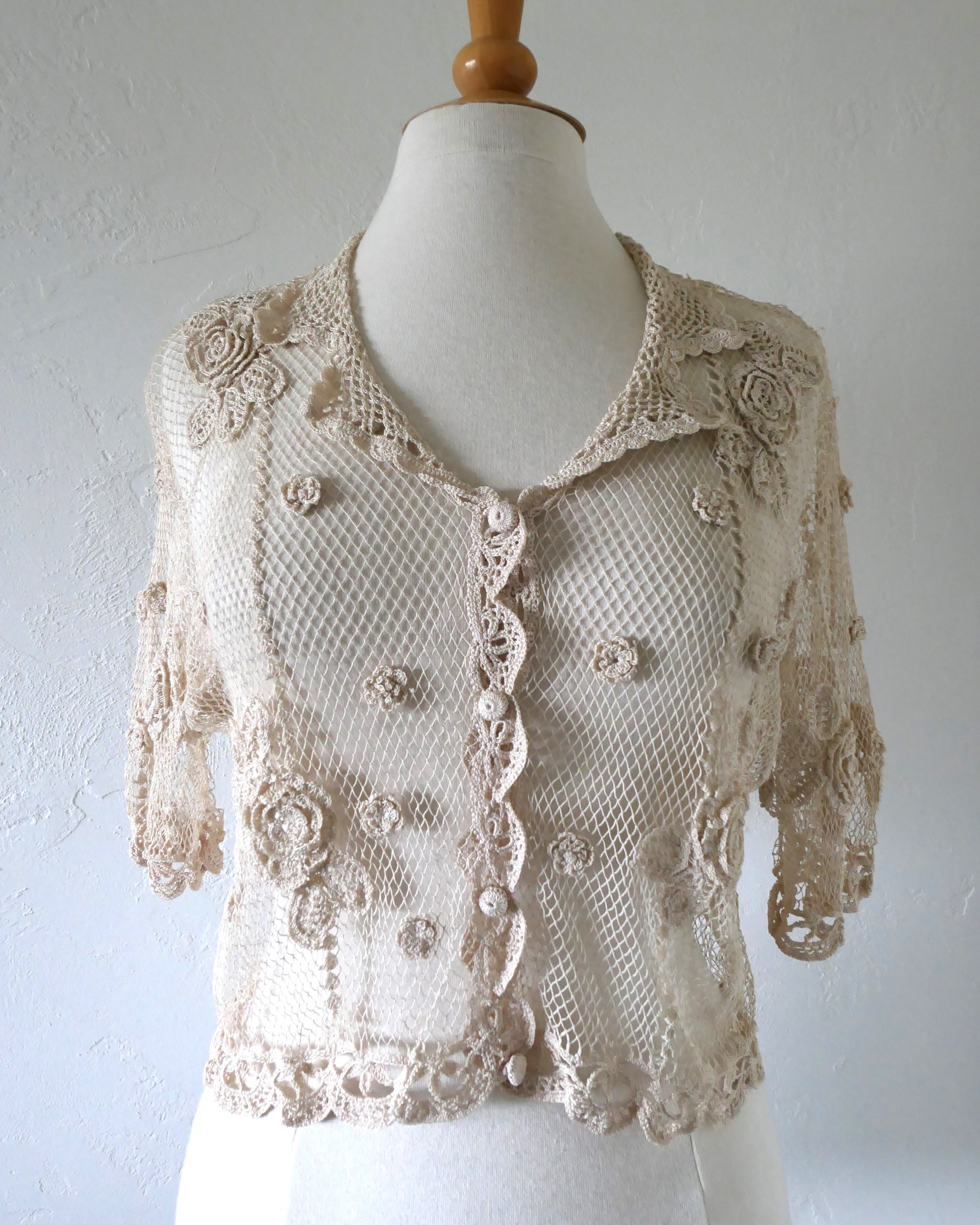 Lim's VIntage natural colored cropped crochet cardigan with carnation floral motif, notched collar, and scalloped edging around sleeve hem and bottom hem. 