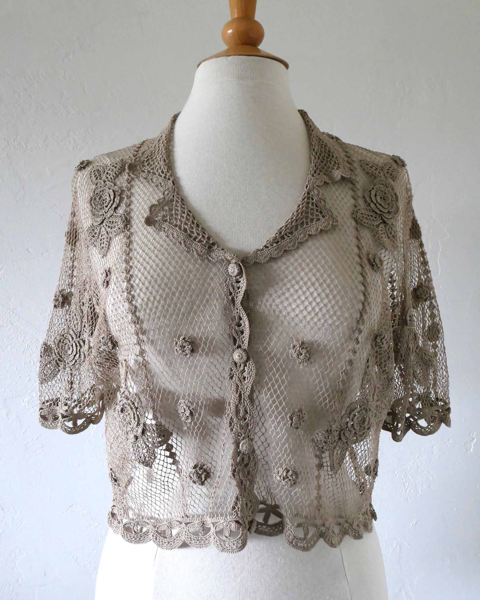 Lim's VIntage taupe colored cropped crochet cardigan with carnation floral motif, notched collar, and scalloped edging around sleeve hem and bottom hem. One size.