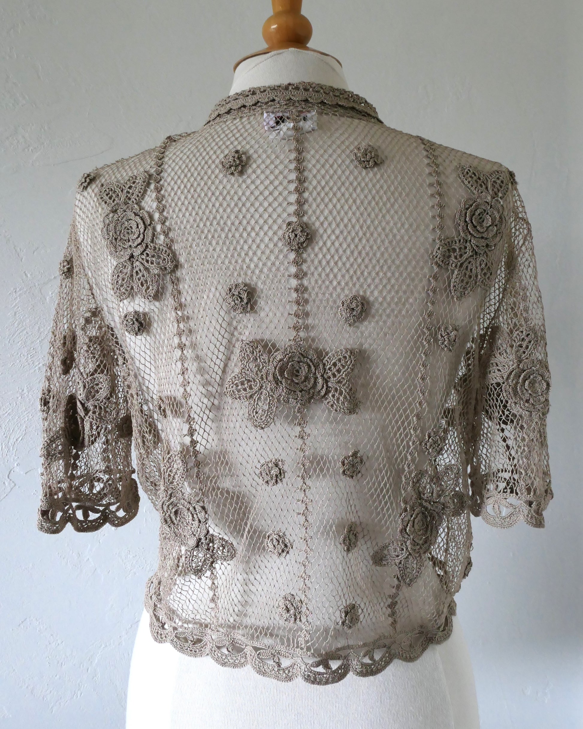 Lim's VIntage taupe colored cropped crochet cardigan with carnation floral motif, notched collar, and scalloped edging around sleeve hem and bottom hem. 