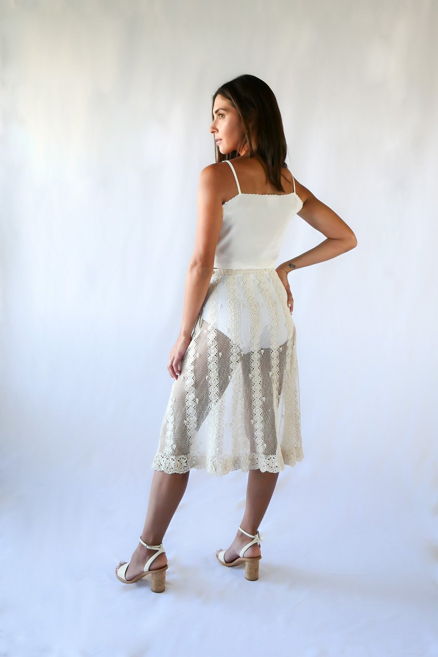 This Lim's Vintage crochet skirt is made with very fine threads to form a delicate net-like pattern throughout, coupled with vertical stripes made of linking pinwheel shaped circles, and a floral motif hem. The skirt is slightly stretchable and comes with a comfortable elastic waistband and buttons up one side of the waist.