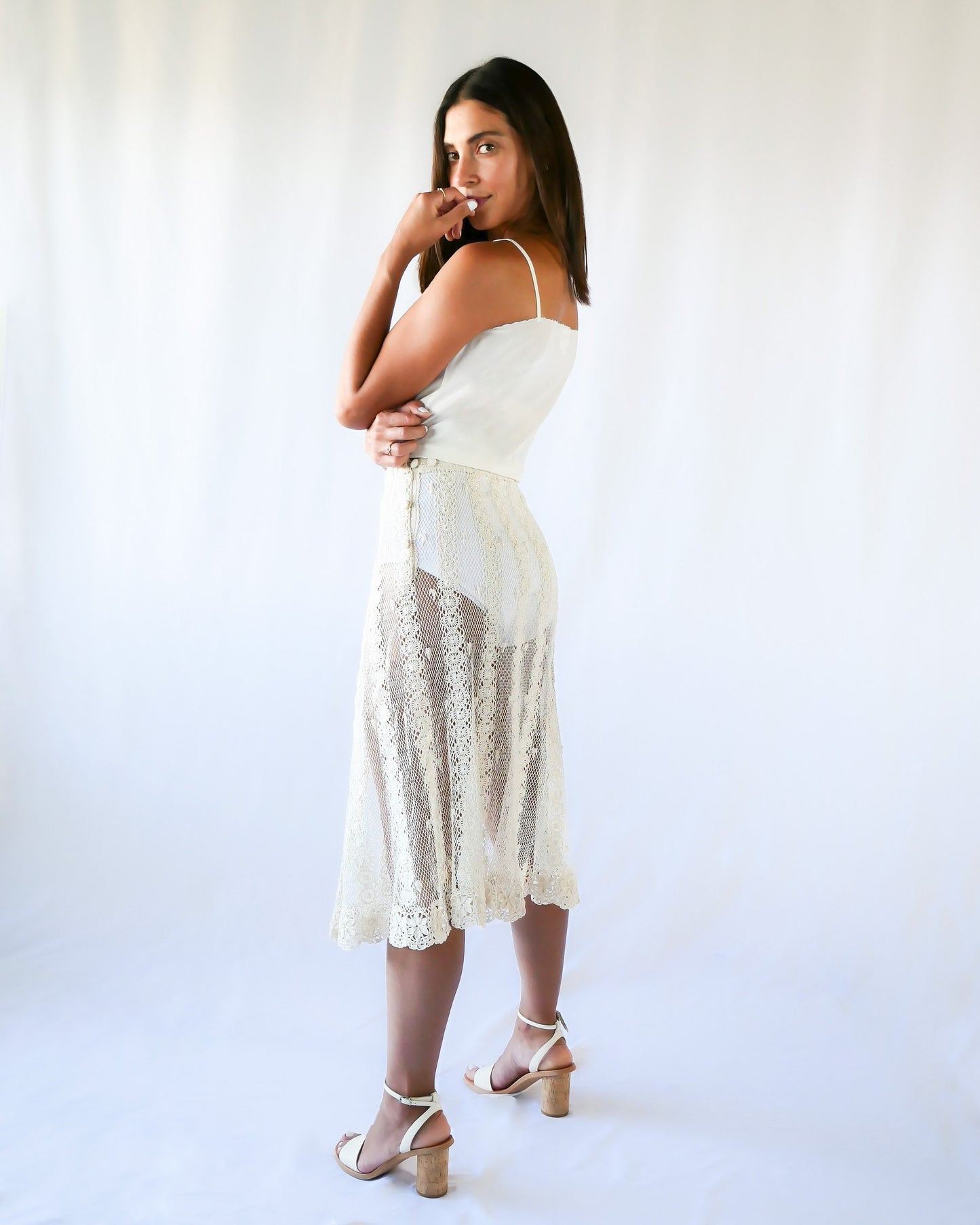 This Lim's Vintage crochet skirt is made with very fine threads to form a delicate net-like pattern throughout, coupled with vertical stripes made of linking pinwheel shaped circles, and a floral motif hem. The skirt is slightly stretchable and comes with a comfortable elastic waistband and buttons up one side of the waist.