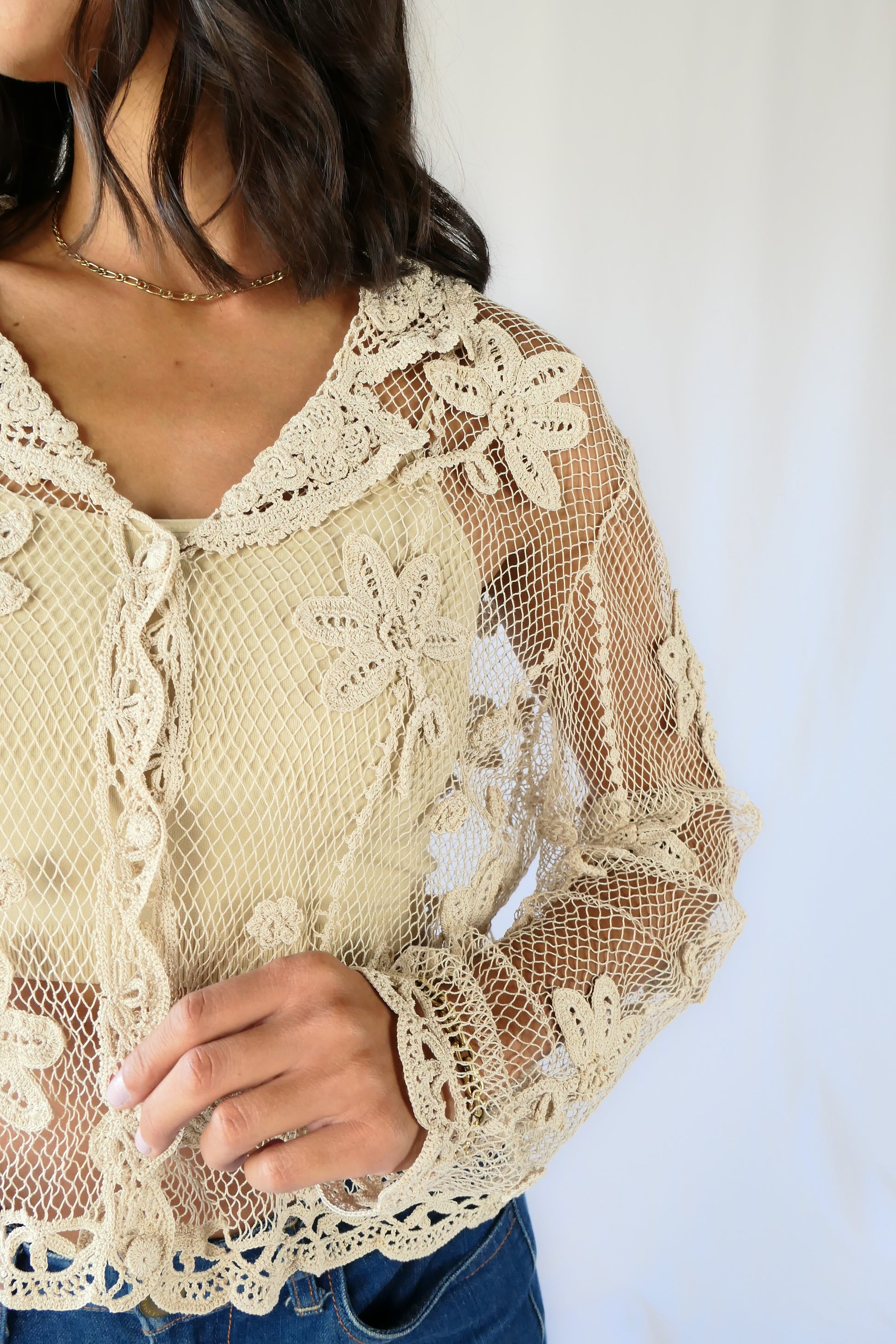 A sheer, hand crocheted Lim's Vintage original long sleeve cardigan with a wide notched collar and daisy floral motif design throughout. Pair it with a tank top, jeans, and boots or sandals for a fresh, boho chic look.