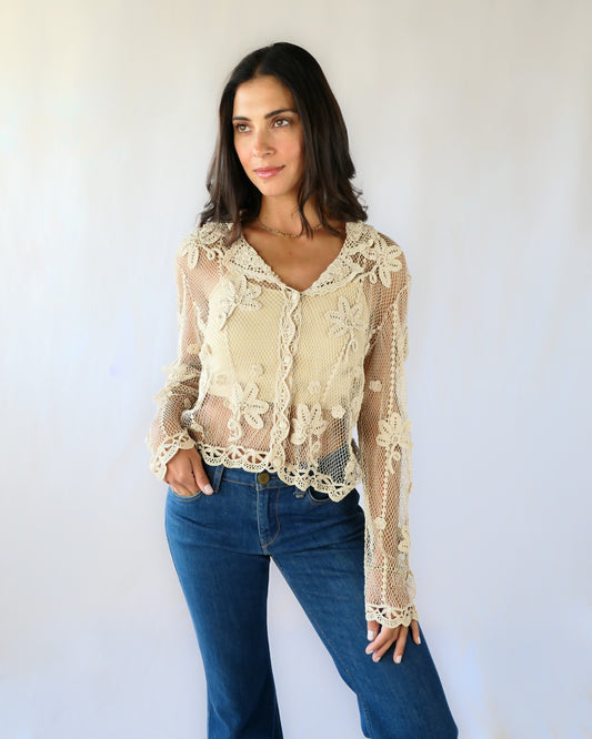 A sheer, hand crocheted Lim's Vintage original long sleeve cardigan with a wide notched collar and daisy floral motif design throughout. Pair it with a tank top, jeans, and boots or sandals for a fresh, boho chic look.