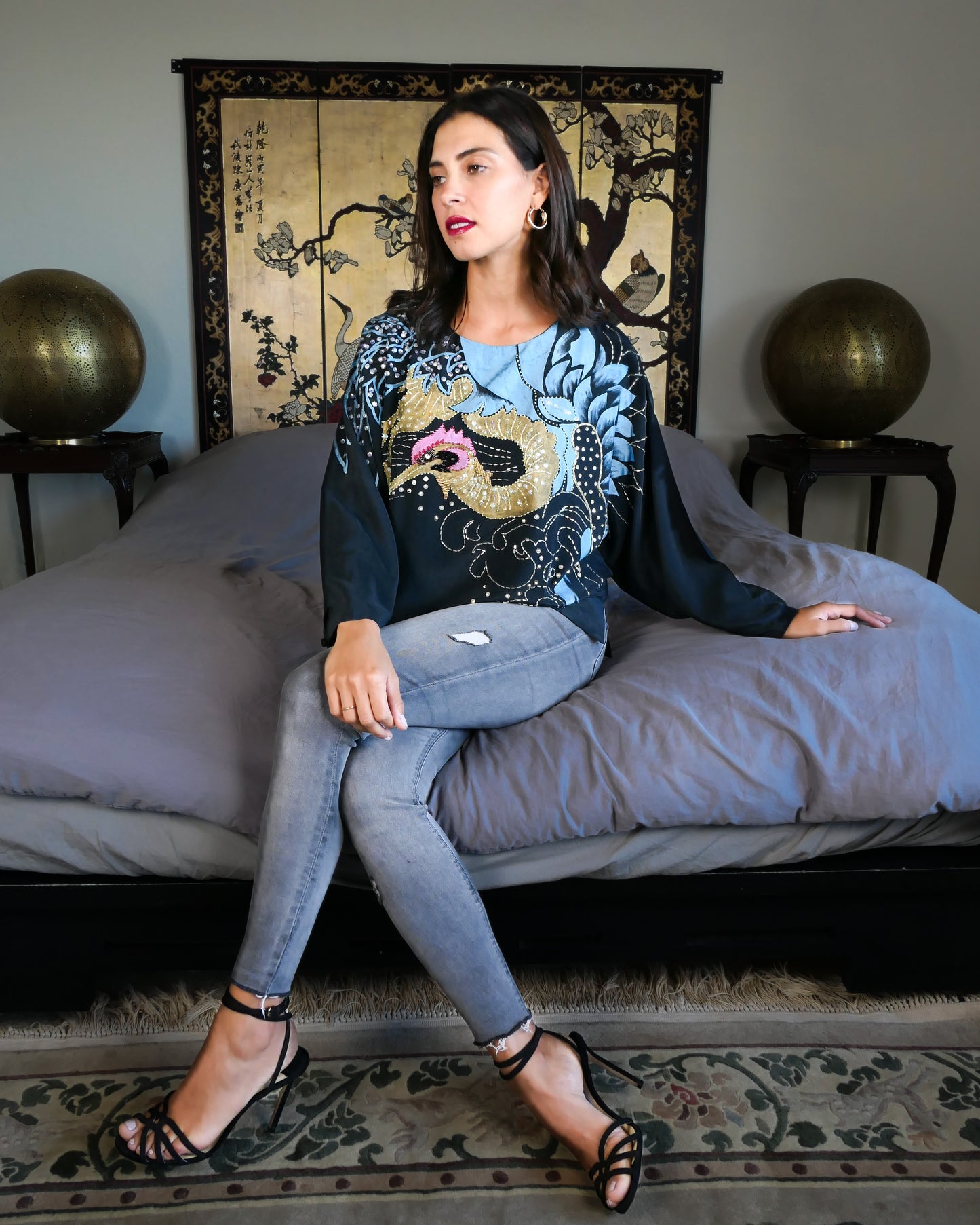 Make a bold party statement in this black silk pullover top with a hand-painted gold and turquoise phoenix, embellished with iridescent, pink, black, and clear colored sequins. In Chinese culture, the phoenix is a symbol of virtue, harmony, balance and peace. This beautifully made top is sure to bring harmony to your wardrobe as well!