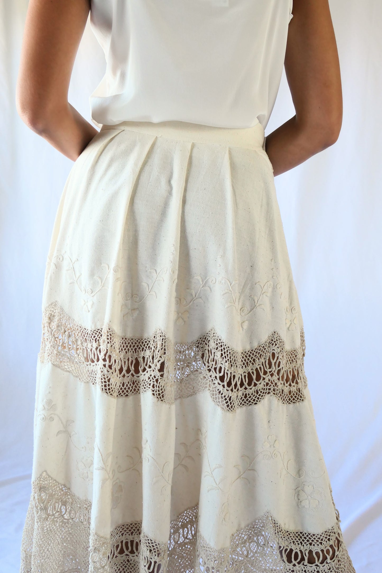Picture yourself strolling through a sunlit Mediterranean village in this beautiful raw silk maxi skirt - an original Lim's skirt from the 1990s - with hand embroidered floral embellishments and hand crocheted trim. This skirt has a fitted, non-elastic waistband and is semi-pleated at the waist with three crochet buttons going up the side of the skirt. Measurements: Fits a size XS to Small Waist 26" Skirt length 33", hip 50" Color: Natural Material: Raw silk and cotton