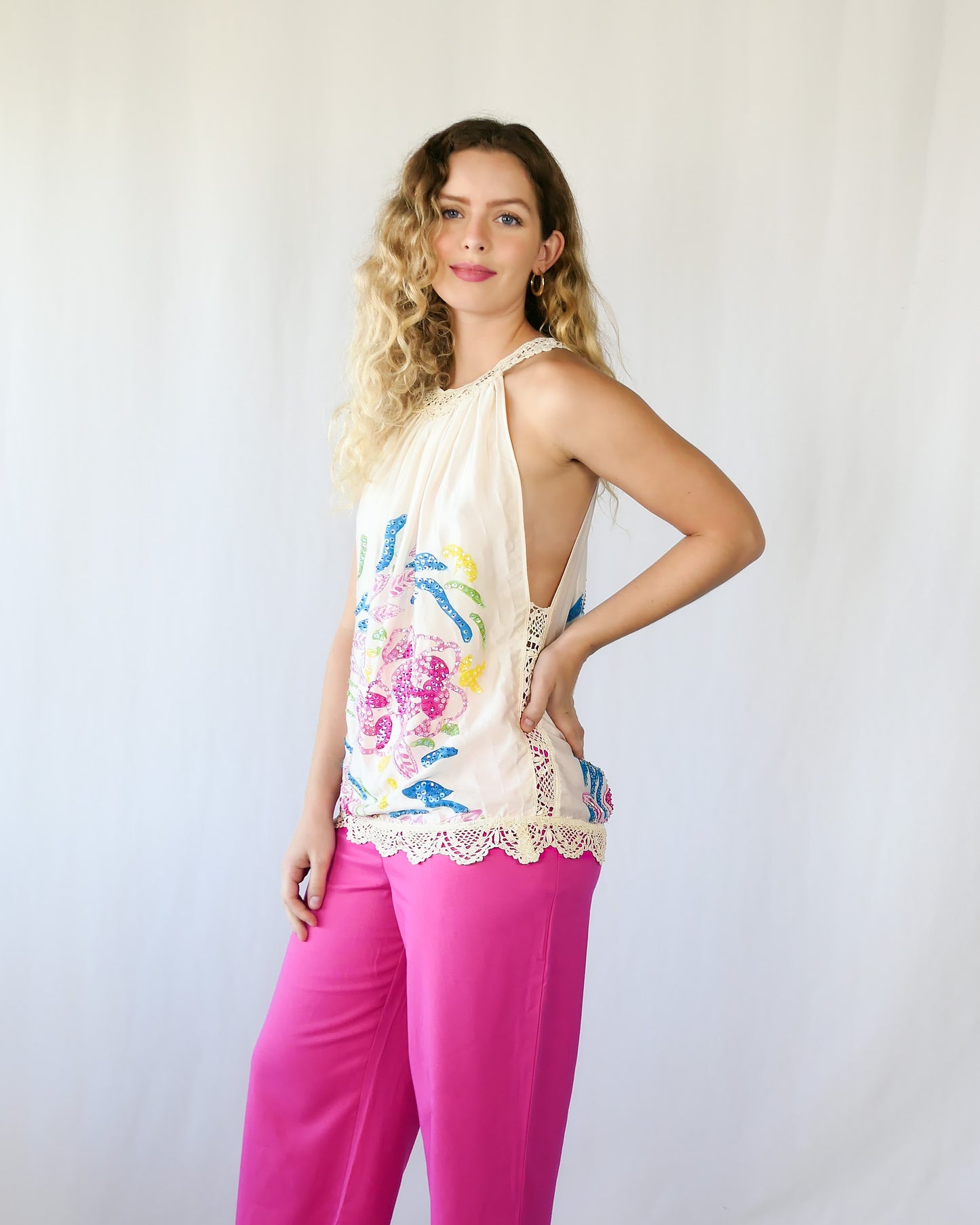 Show off your playful, whimsical side with this multicolored, handpainted and hand sequined silk halter top. Comes with hand crocheted trim at the hemline and neckline, and buttons up at the back. Dress it up with a pair of matching pink pants or silk ivory colored wide leg pants and pink or ivory colored heels.  Size: Small  Measurements:  Bust 41” Hem 40" Length 27” Color: Ivory  Material: 100% silk with cotton crochet trim.  Made by Lim's Vintage.