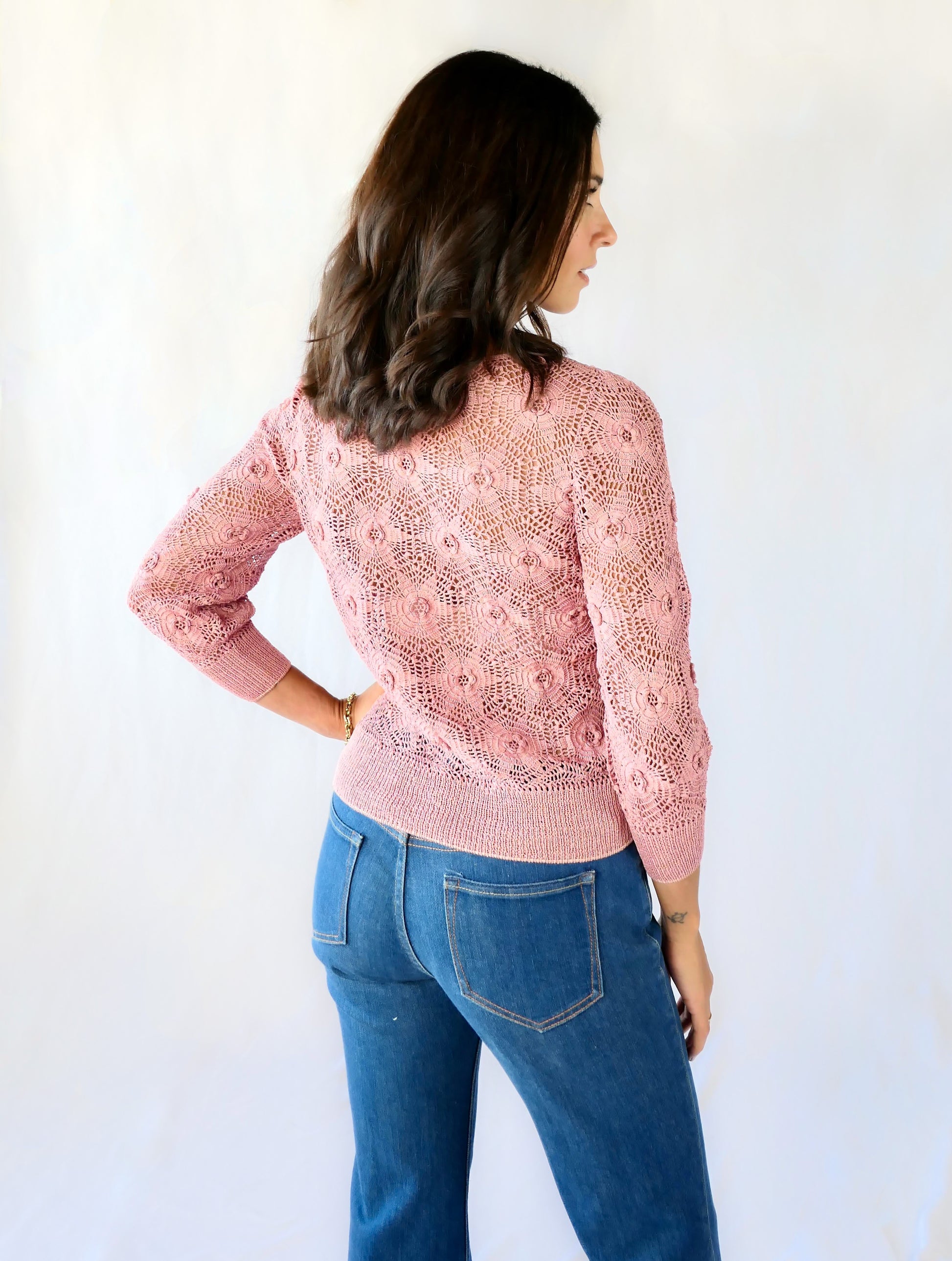 Back view. Your everyday fitted sweater with a twist. Hand crocheted crewneck sweater in a soft muted rose color, with star shaped flowers and elastic banding at the hip and wrists.  Our model is 5'4" and wears a size Small. 