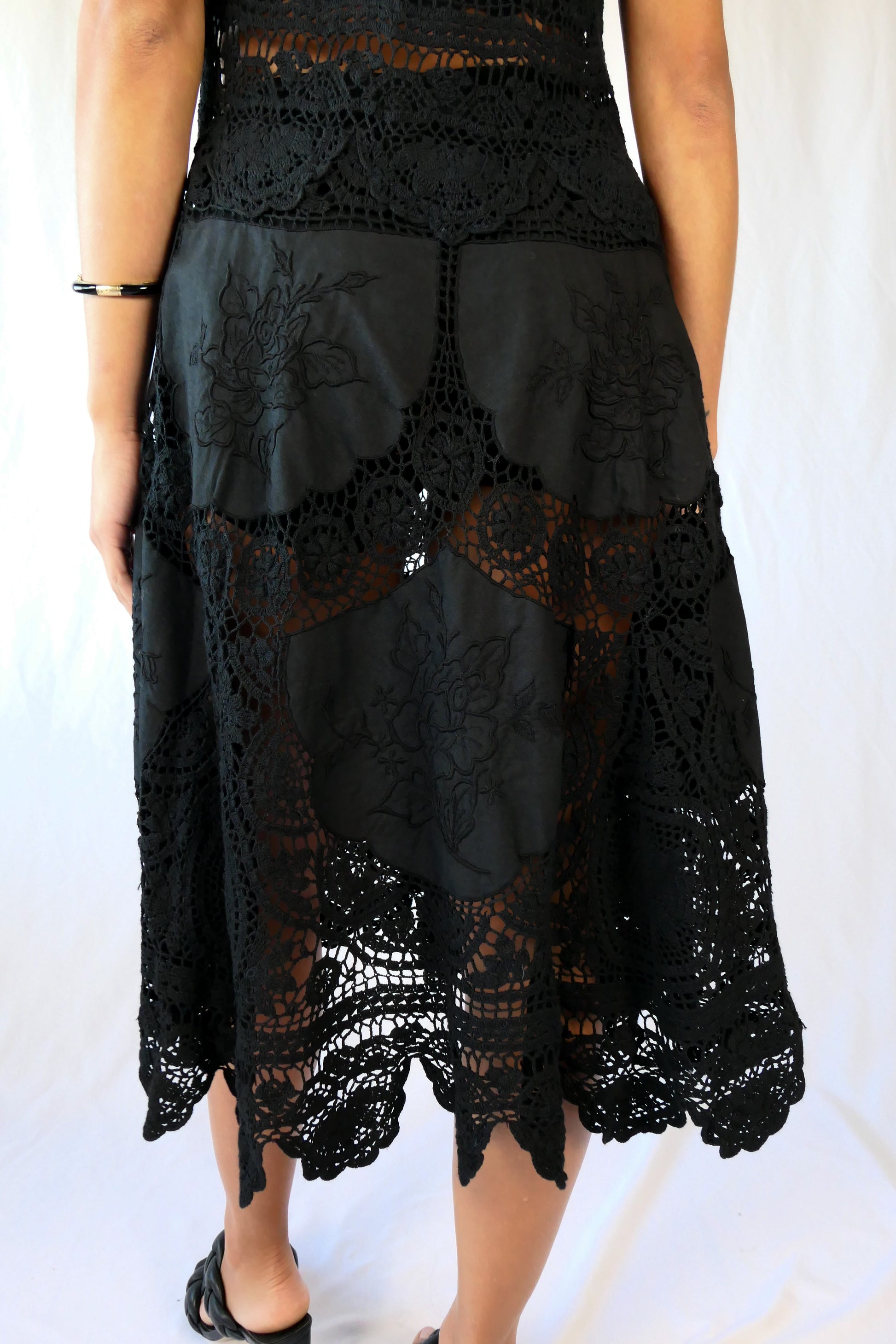 Skirt detail of the back. This Little Black Dress with detailed hand crochet and embroidery work lends itself a vintage flair.  The dress can be buttoned up the front or back, has a flattering fit at the waist, and flares out towards the hem.  Wear it as a cocktail dress with black heels or sandals, or as a beach coverup.  