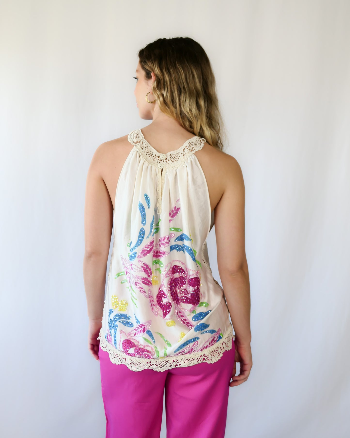 Show off your playful, whimsical side with this multicolored, handpainted and hand sequined silk halter top. Comes with hand crocheted trim at the hemline and neckline, and buttons up at the back. Dress it up with a pair of matching pink pants or silk ivory colored wide leg pants and pink or ivory colored heels.  Size: Small  Measurements:  Bust 41” Hem 40" Length 27” Color: Ivory  Material: 100% silk with cotton crochet trim.  Made by Lim's Vintage.