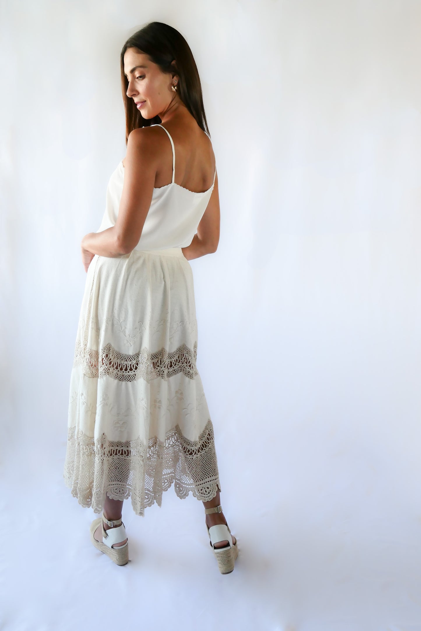 Picture yourself strolling through a sunlit Mediterranean village in this beautiful raw silk maxi skirt - an original Lim's skirt from the 1990s - with hand embroidered floral embellishments and hand crocheted trim. This skirt has a fitted, non-elastic waistband and is semi-pleated at the waist with three crochet buttons going up the side of the skirt. Measurements: Fits a size XS to Small Waist 26" Skirt length 33", hip 50" Color: Natural Material: Raw silk and cotton