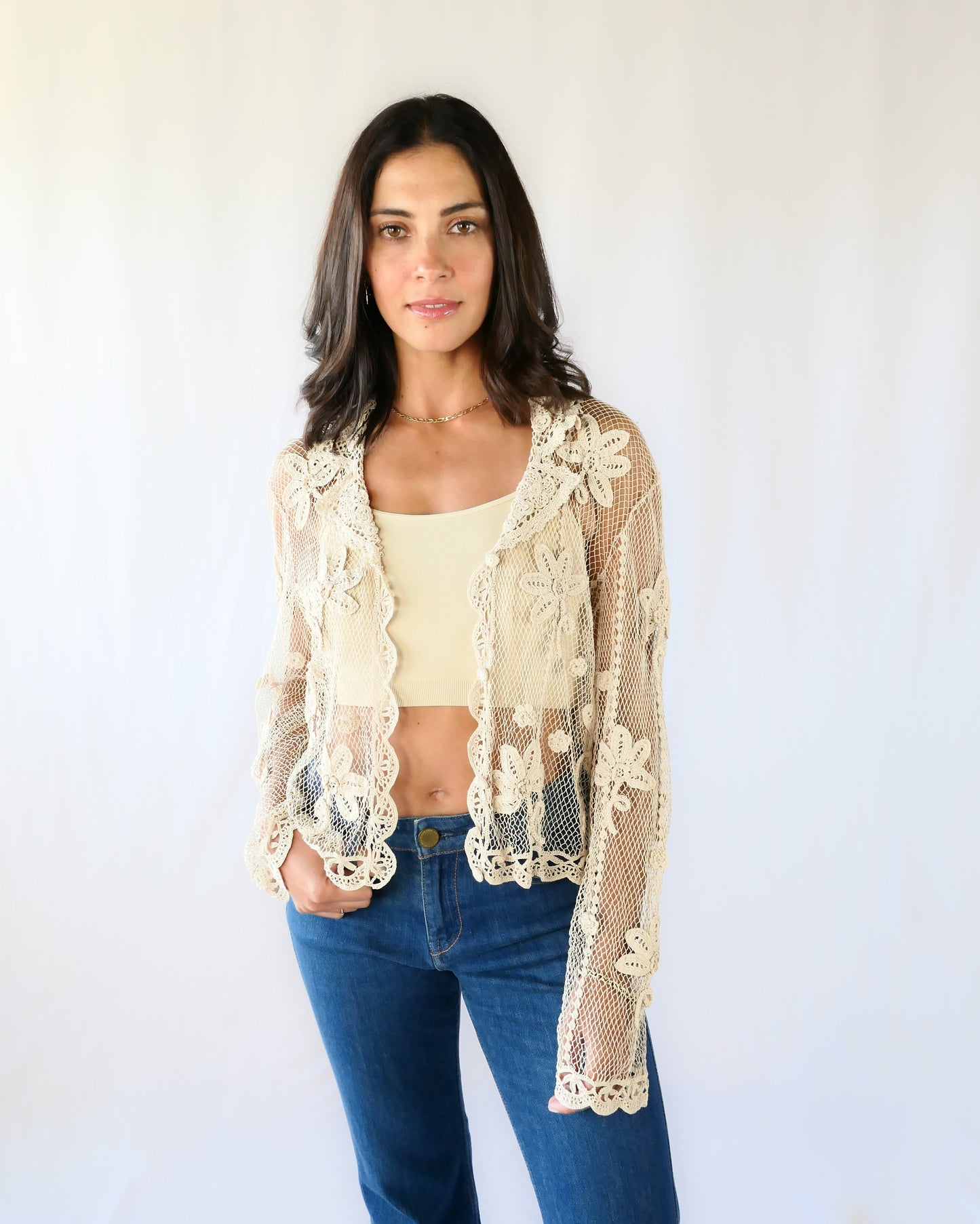 A sheer, hand crocheted Lim's Vintage original long sleeve cardigan with a wide notched collar and daisy floral motif design throughout. Pair it with a tank top, jeans, and boots or sandals for a fresh, boho chic look.  Here the model wears the jacket unbuttoned. 