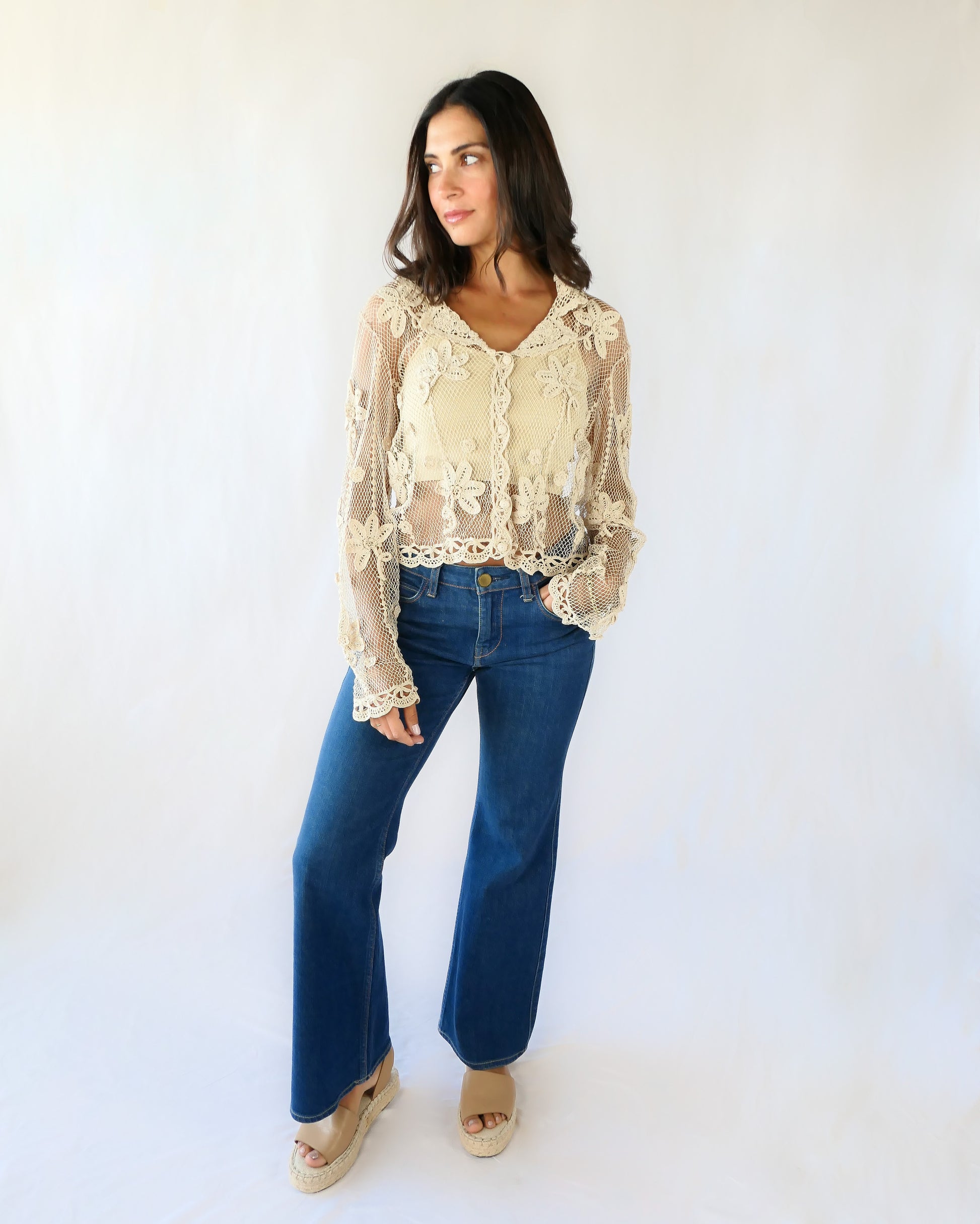 A sheer, hand crocheted Lim's Vintage original long sleeve cardigan with a wide notched collar and daisy floral motif design throughout. Pair it with a tank top, jeans, and boots or sandals for a fresh, boho chic look.